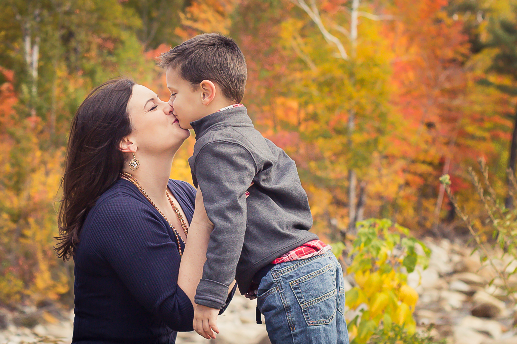 pregnant mom gives son a kiss during outdoor maternity pictures