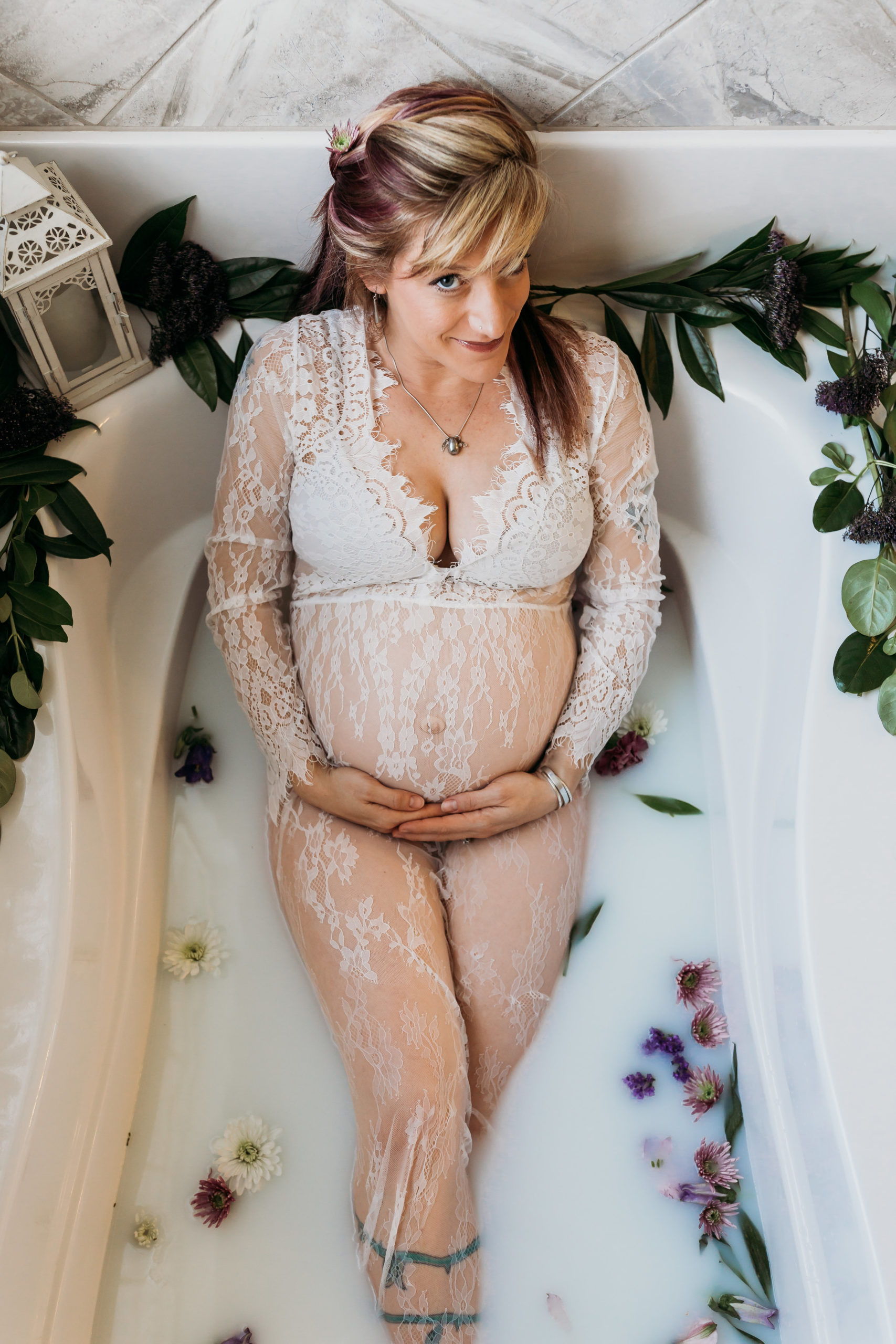 woman holding pregnant belly in milk bath