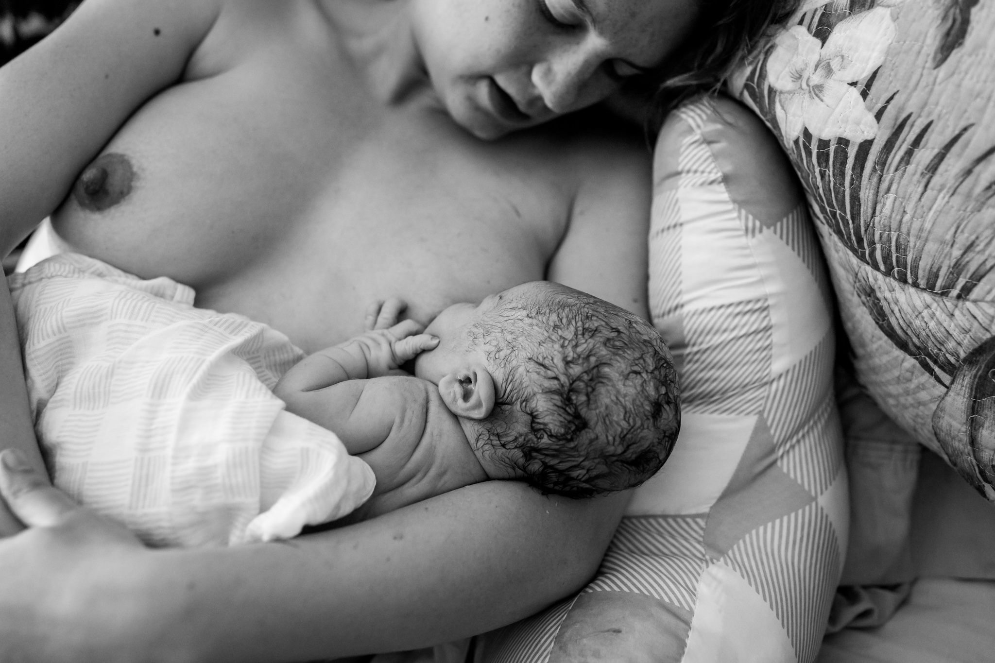 woman cuddles with baby on bed