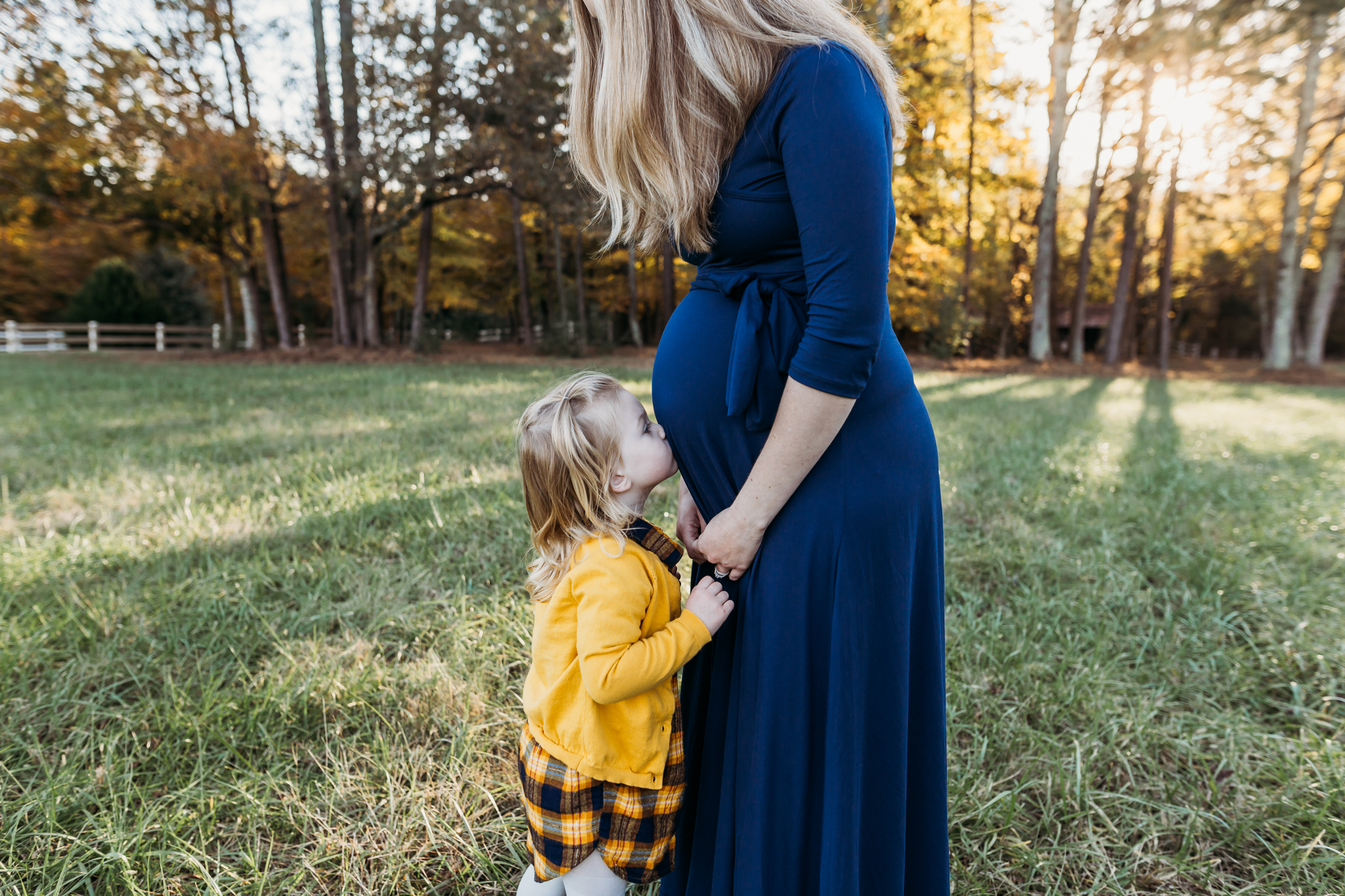 girl kisses pregnant moms belly during maternity photos