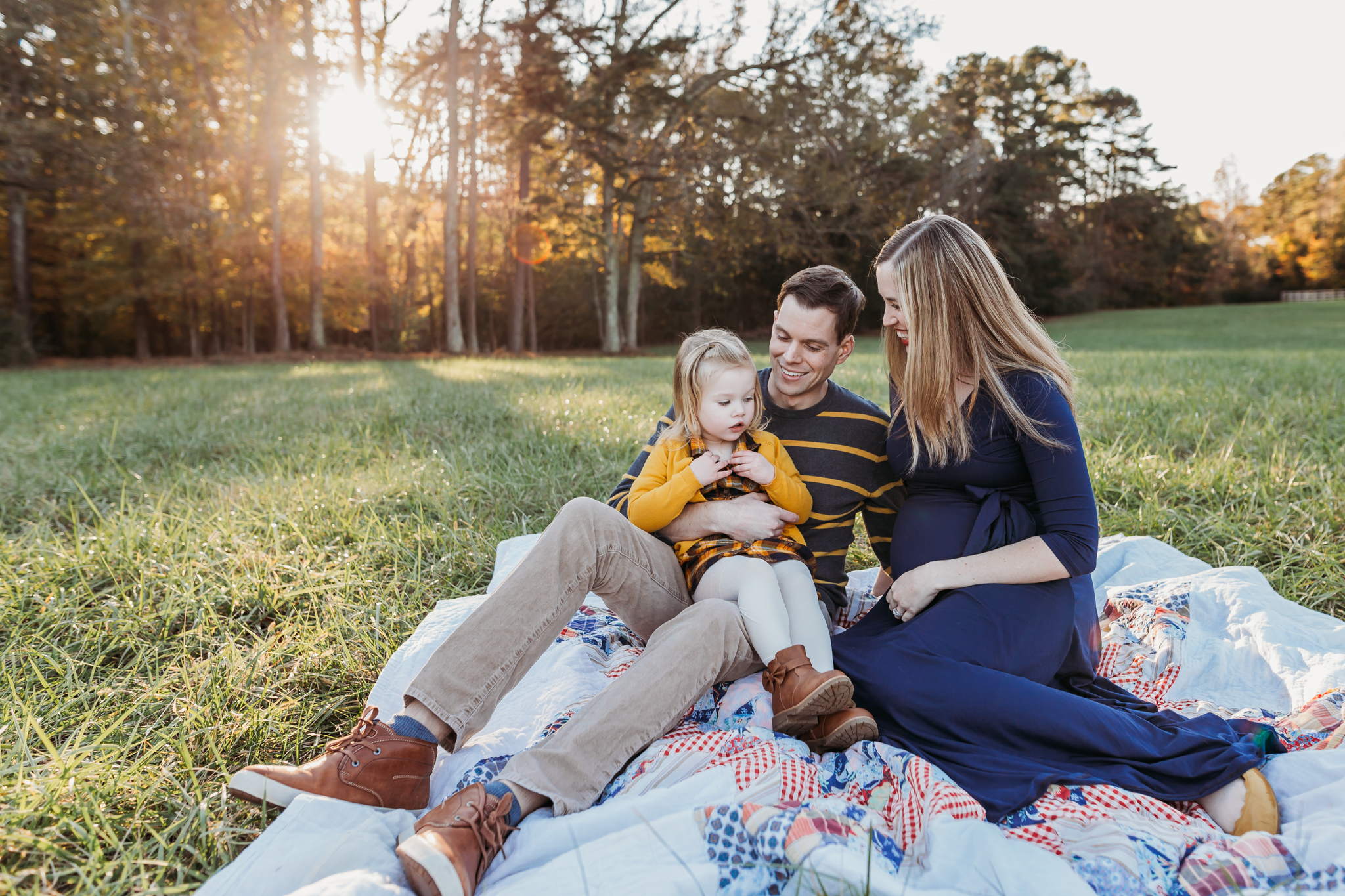 family tickles on blanket in a field