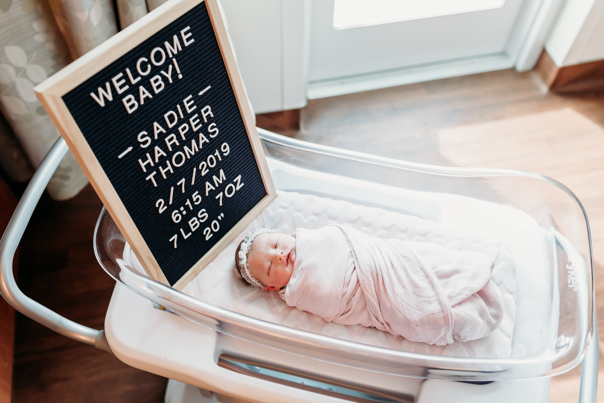 baby girl in bassinet with letter board hospital session
