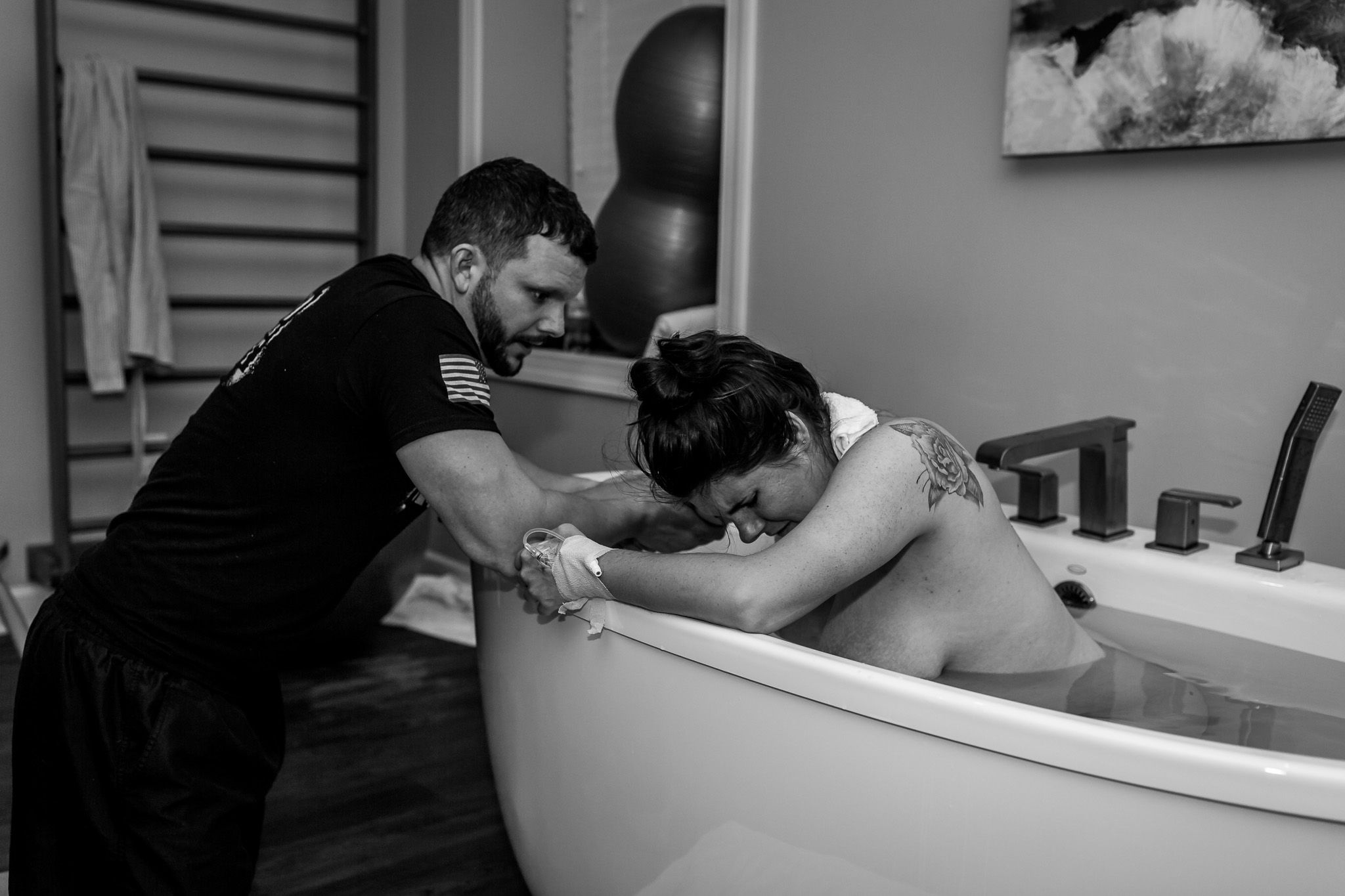 woman labors in birth tub with her husband nearby