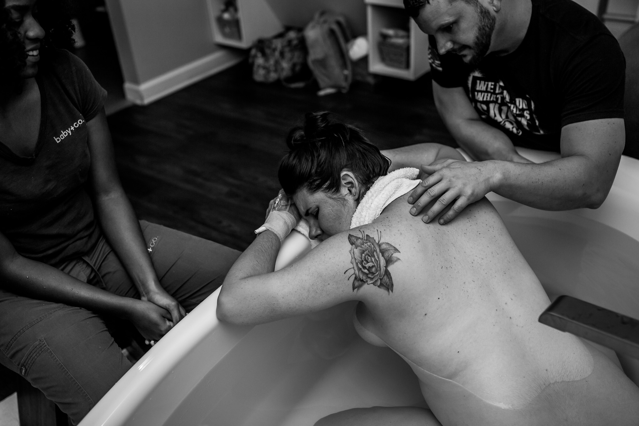 woman puts head down in birth tub as husband rubs her back