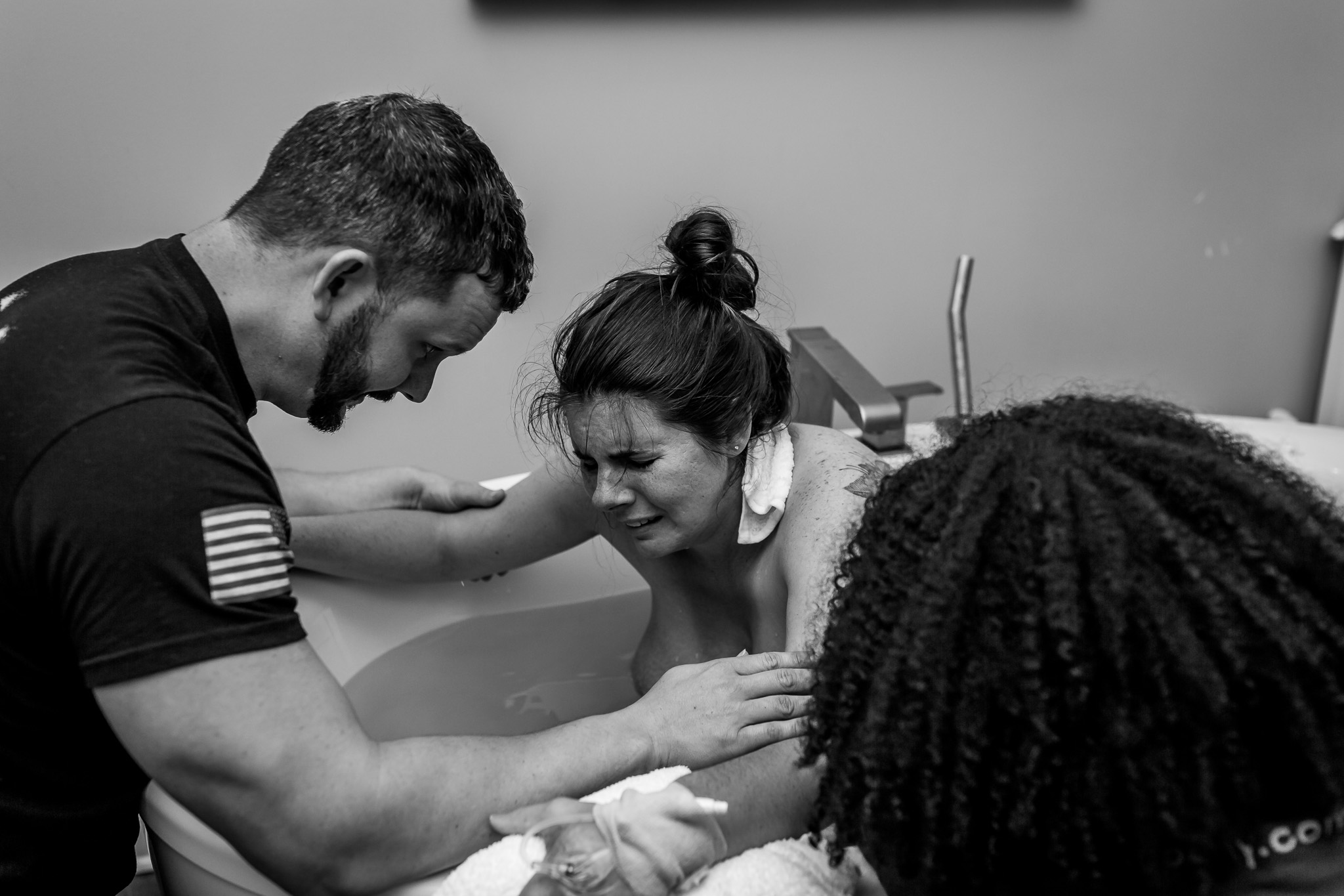 woman hold on to husband as she labors in birth tub
