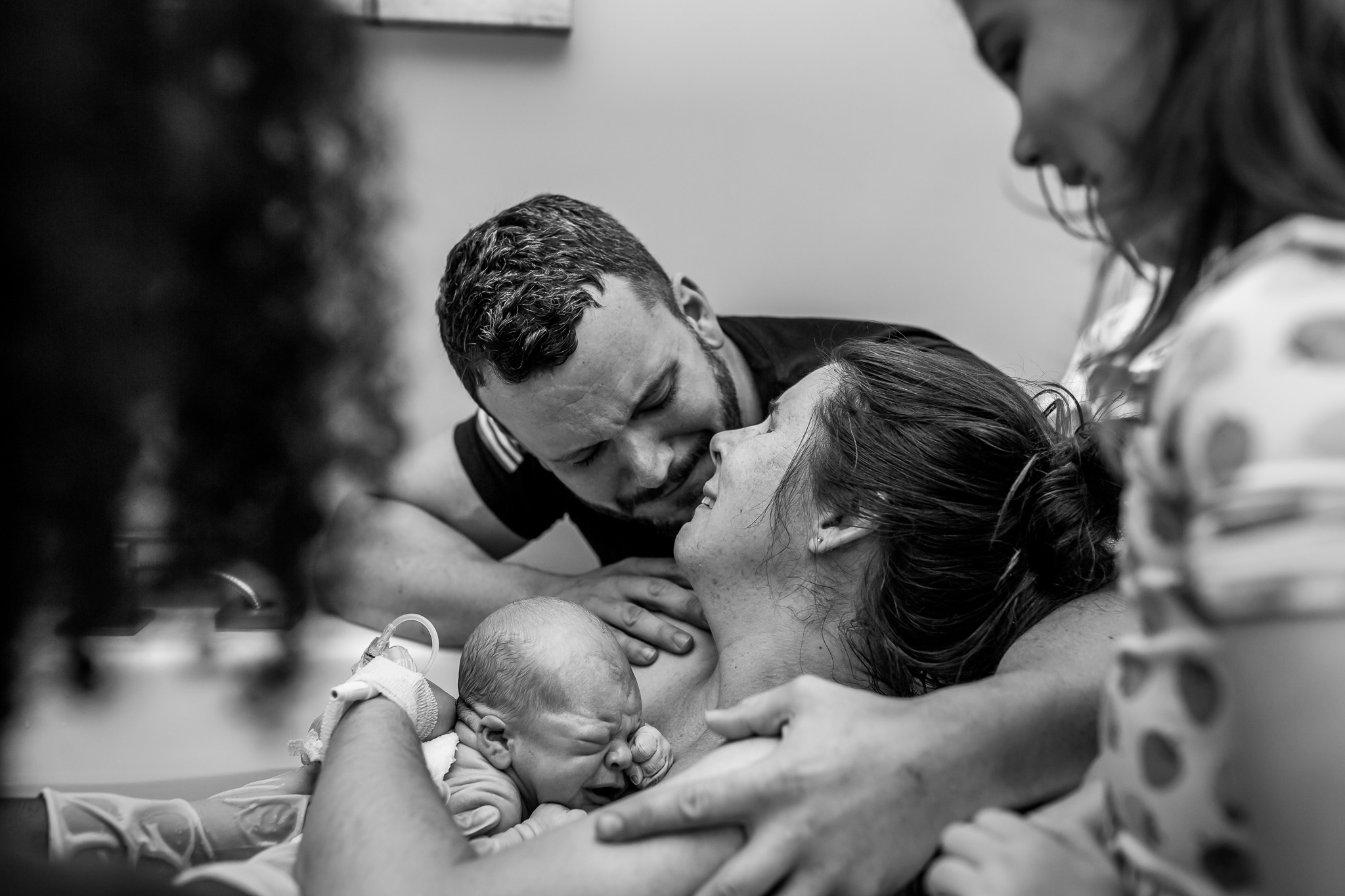 husband and wife kiss after water birth of baby boy