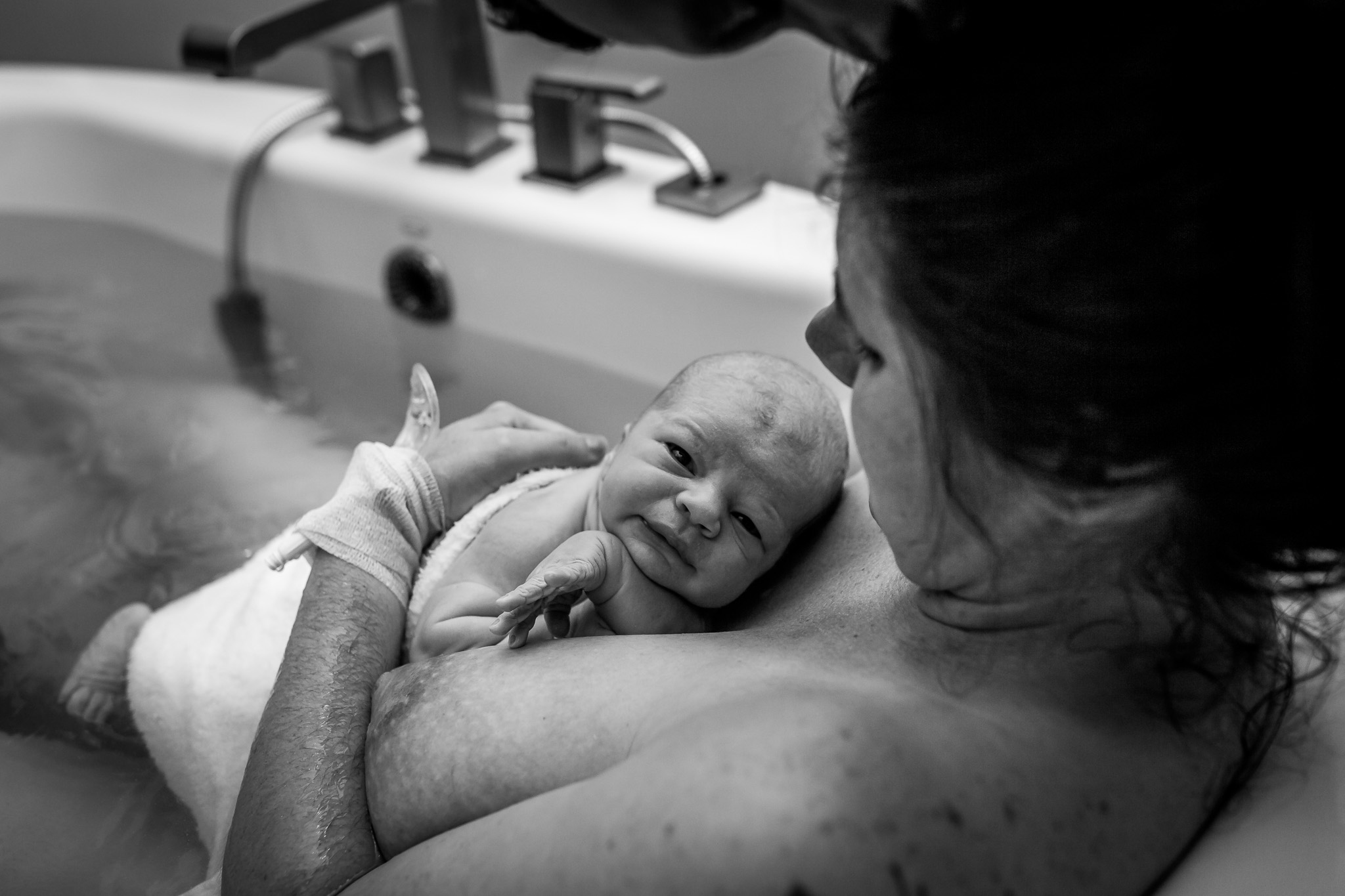 baby looks up from moms chest after water birth