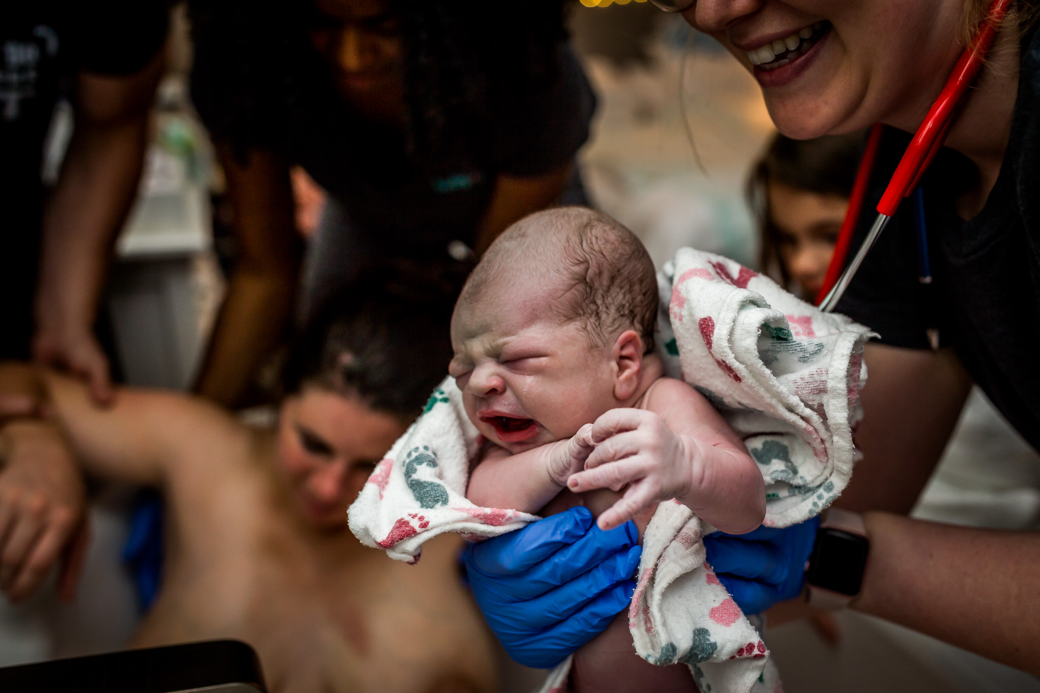 midwife holds up newborn after water birth