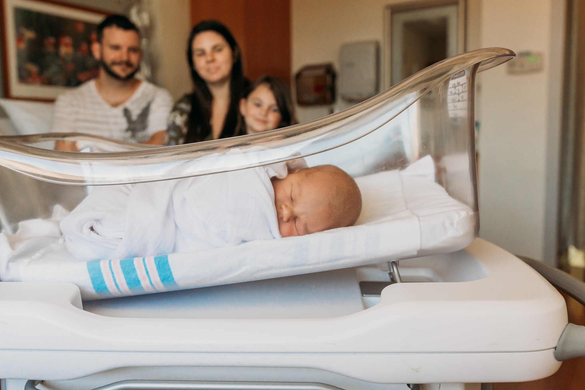 family looks at newborn in hospital bassinet