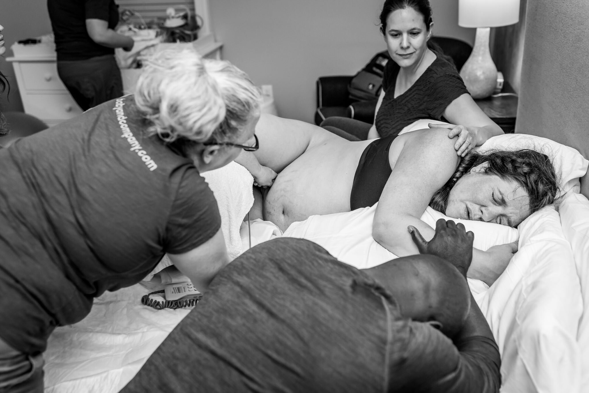 woman comforted during labor by husband doula and midwife