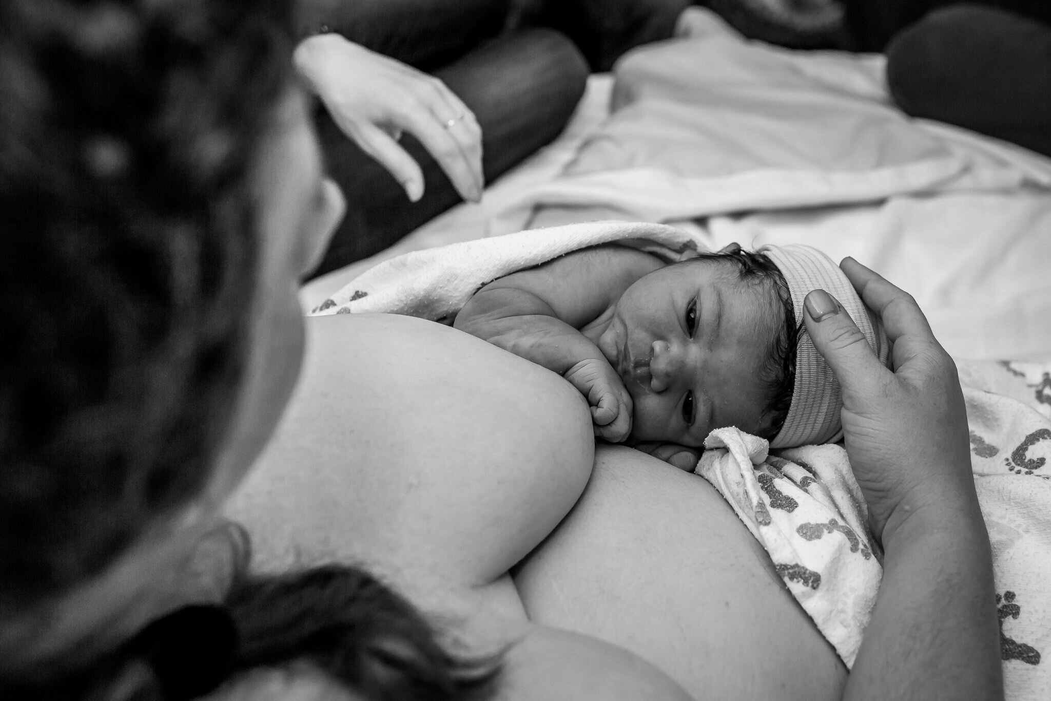 close up of newborn looking up at mom postpartum birth