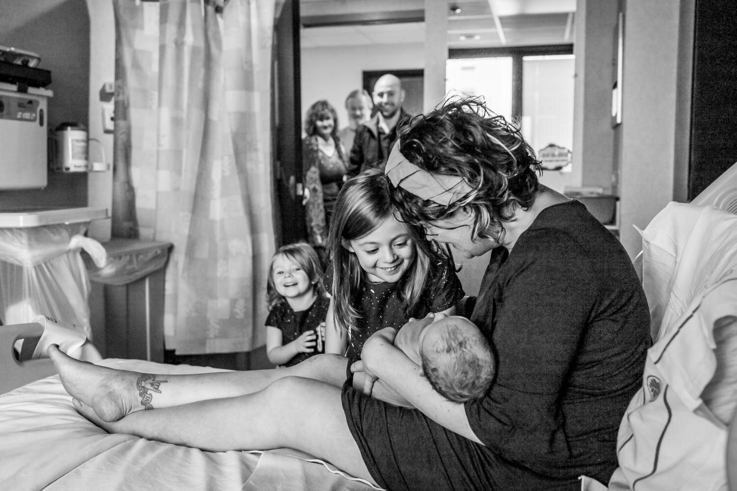 sisters meet newborn brother in hospital bed