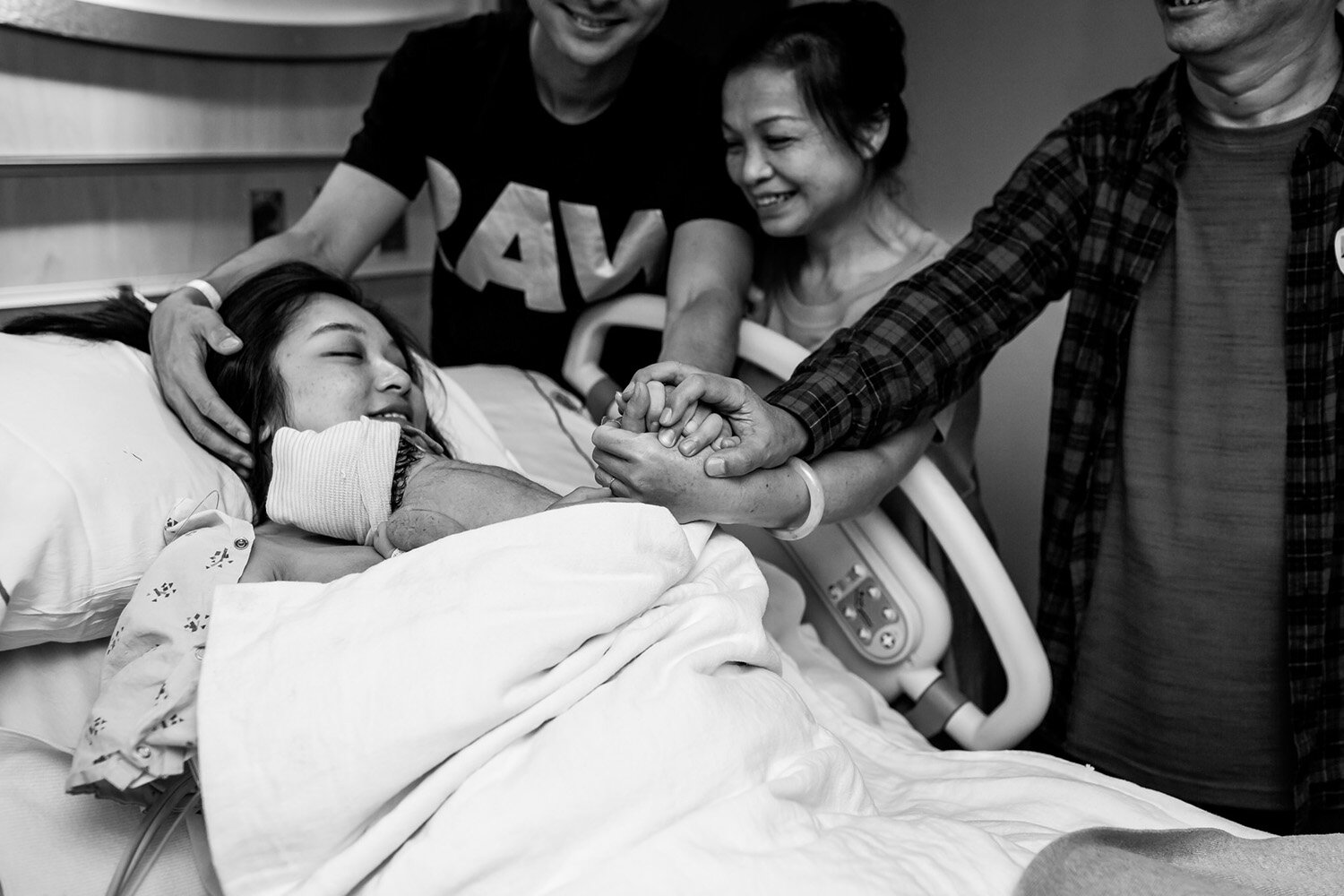 Extended family hold hands after hospital birth