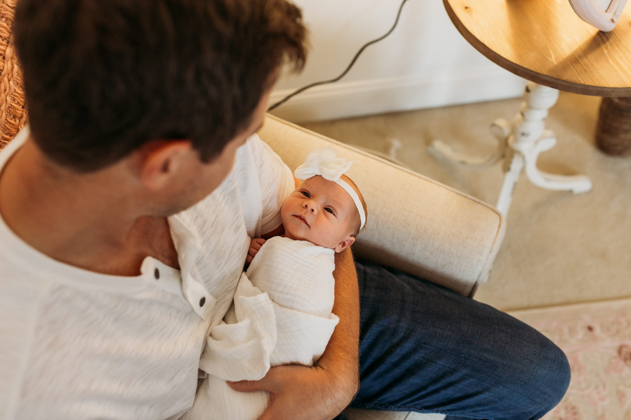 Dad looking at infant daughter lifestyle newborn session