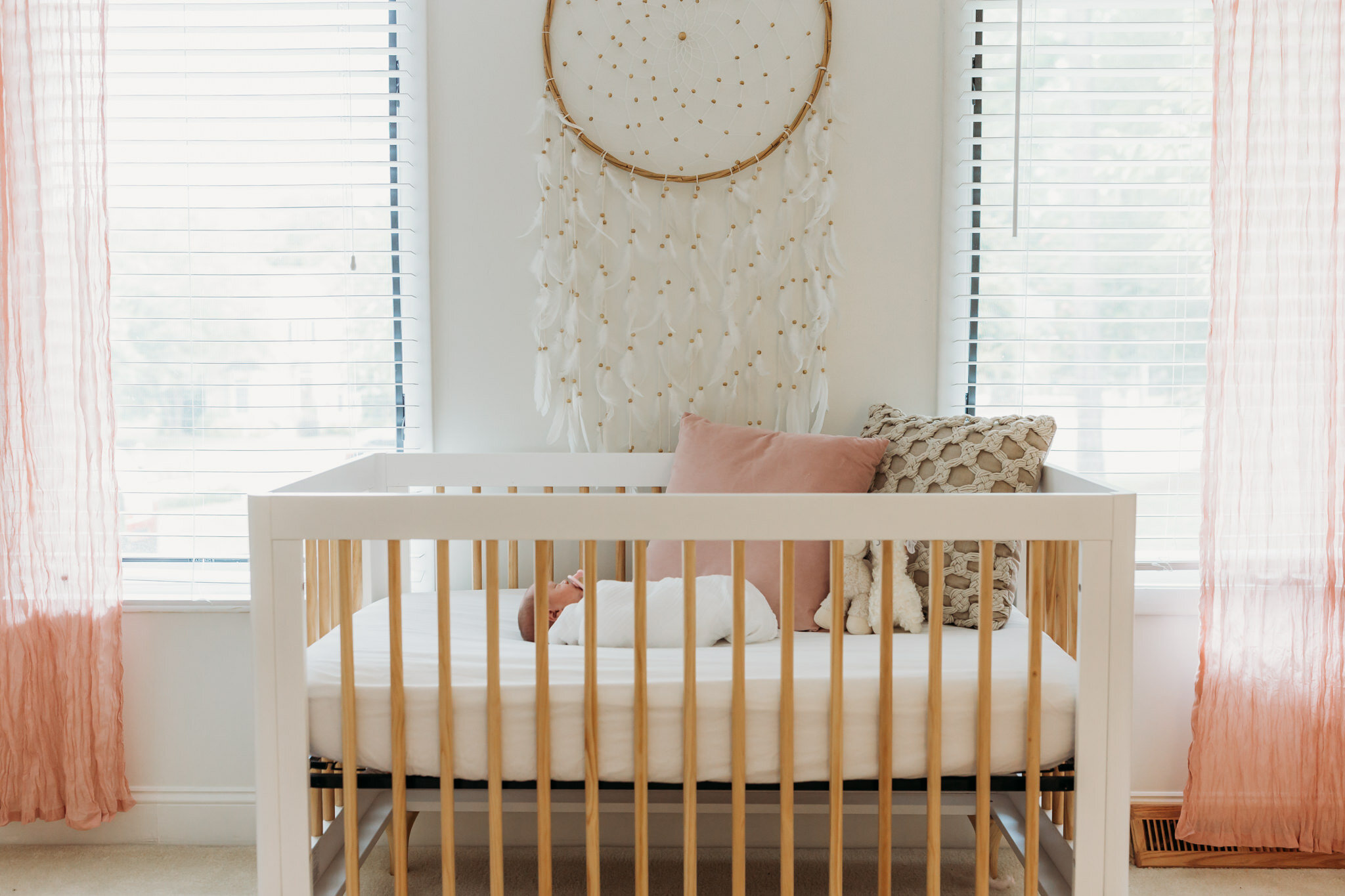 shot of baby laying in crib with dreamcatcher on wall