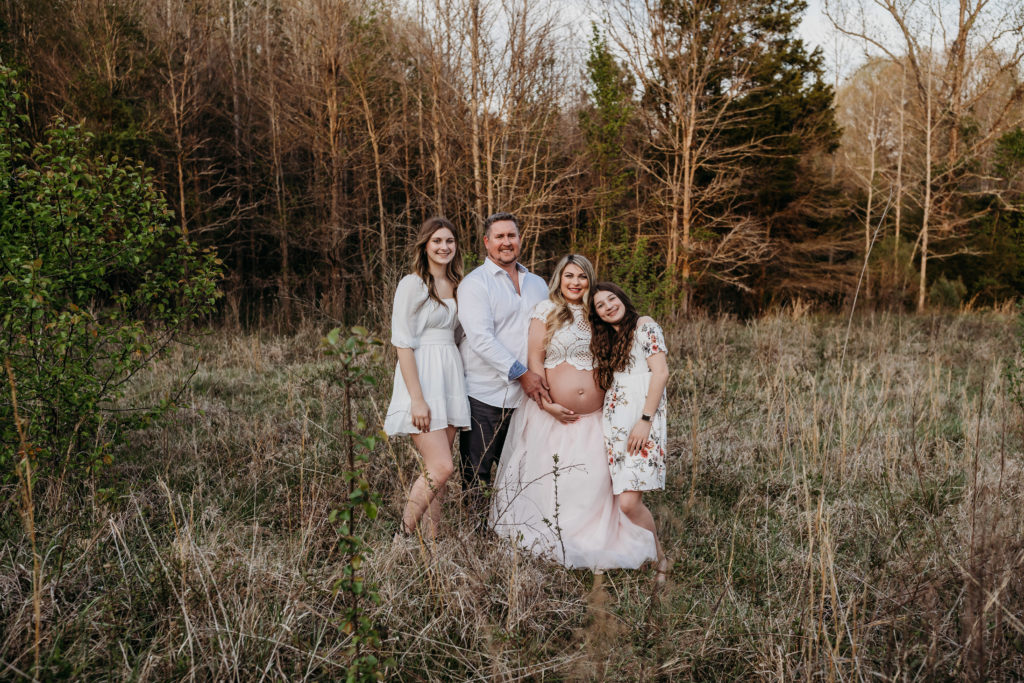 Family standing in field for maternity session