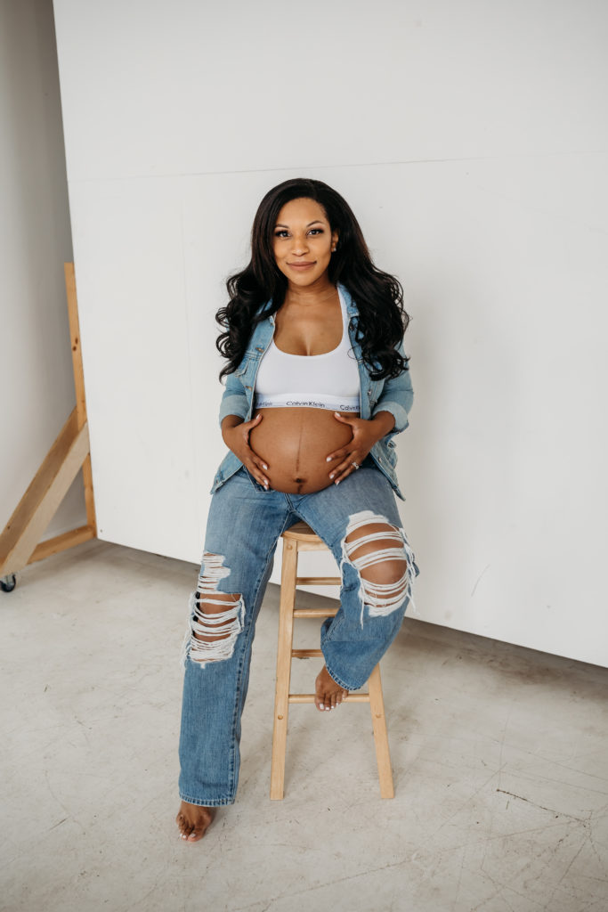 Woman dressed in denim cradling her pregnant belly