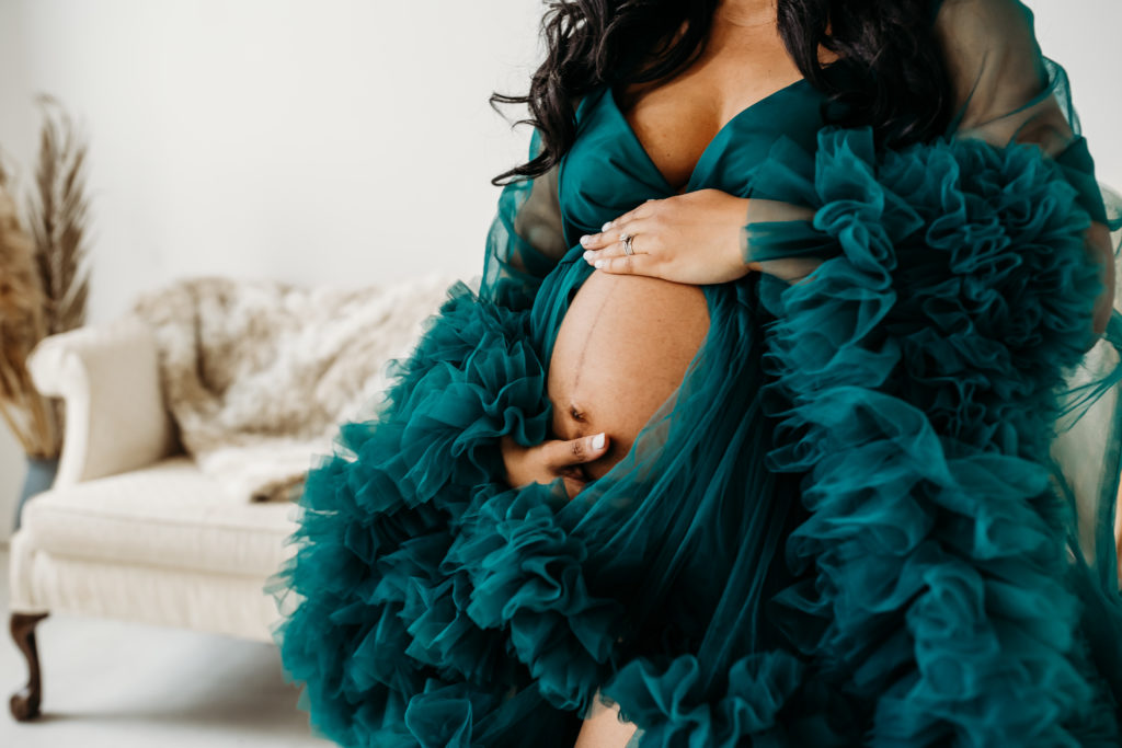 Close up of pregnant belly of woman in teal tulle dress