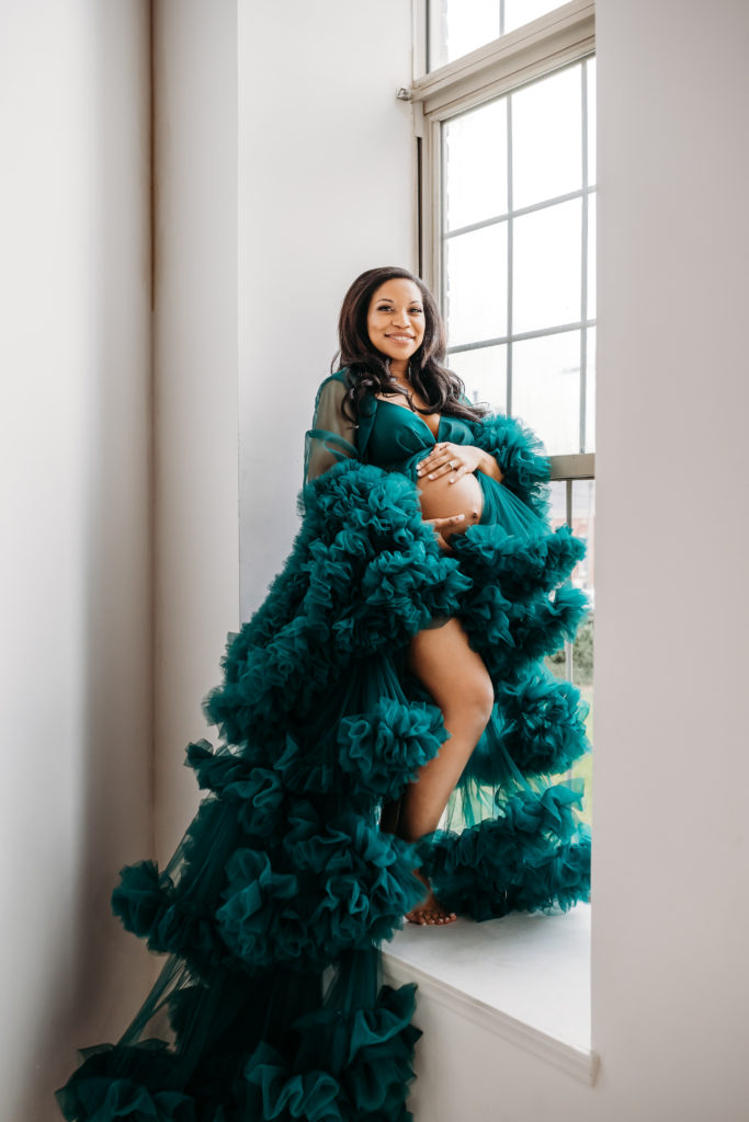 Pregnant mom standing in studio window teal tulle dress maternity session
