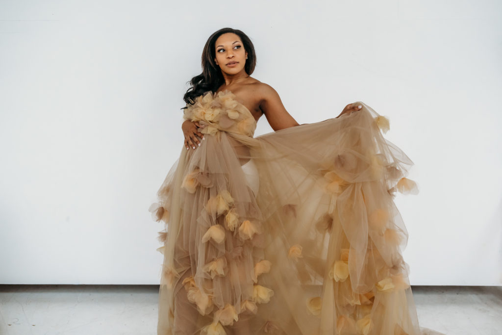 Pregnant mom dressed in cream tulle dress during maternity studio session