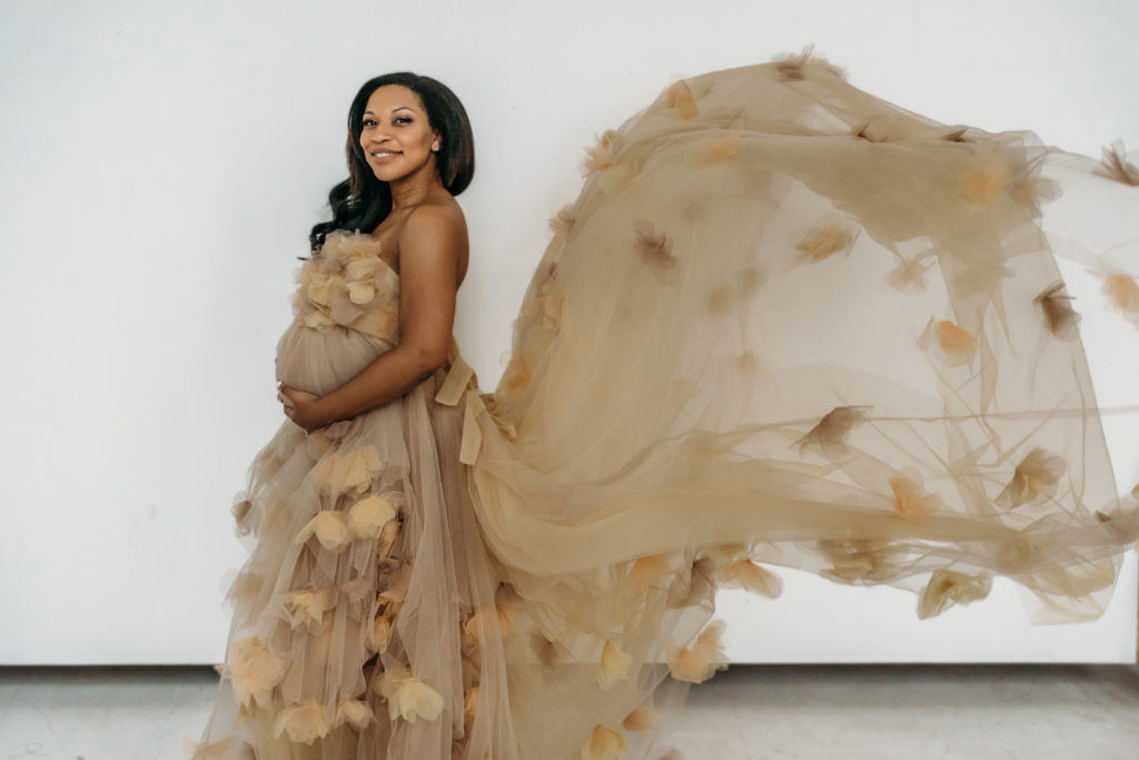 Pregnant mom during studio maternity session in cream tulle maternity dress