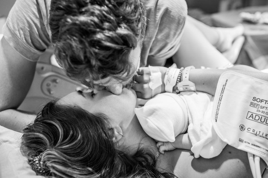 New parents kissing after birth of child at hospital