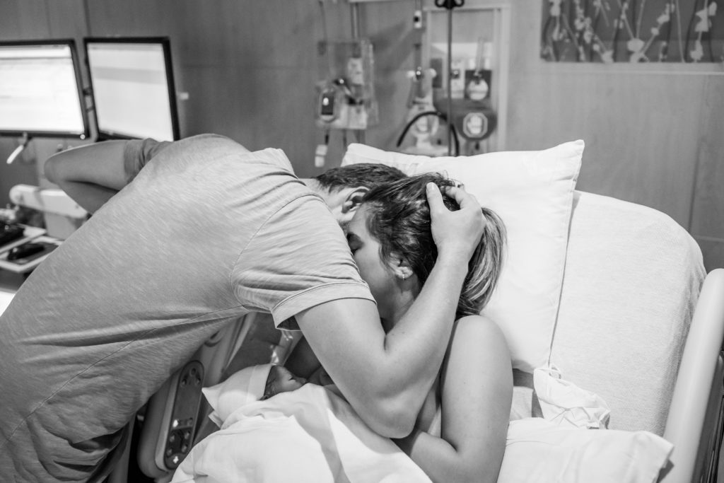 Couple embracing in hospital bed after the birth of their baby