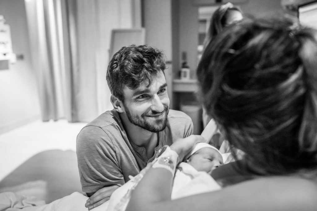 New dad looking lovingly at his wife after she gave birth to baby