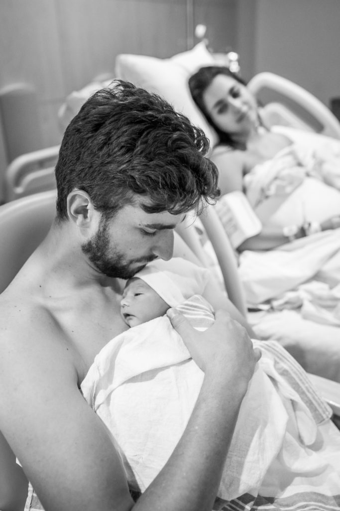 Dad doing skin to skin with baby after birth with mom looking on