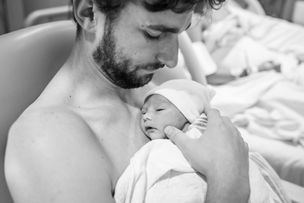 Close up of Dad doing skin to skin with baby after birth with mom looking on