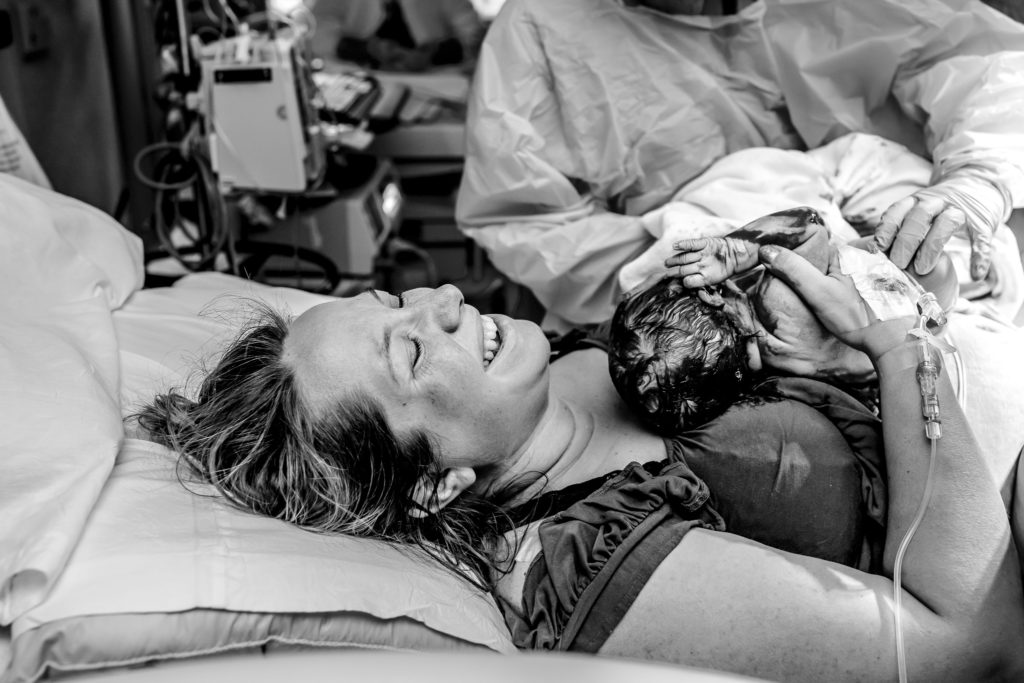 smiling mom holds baby she just gave birth to