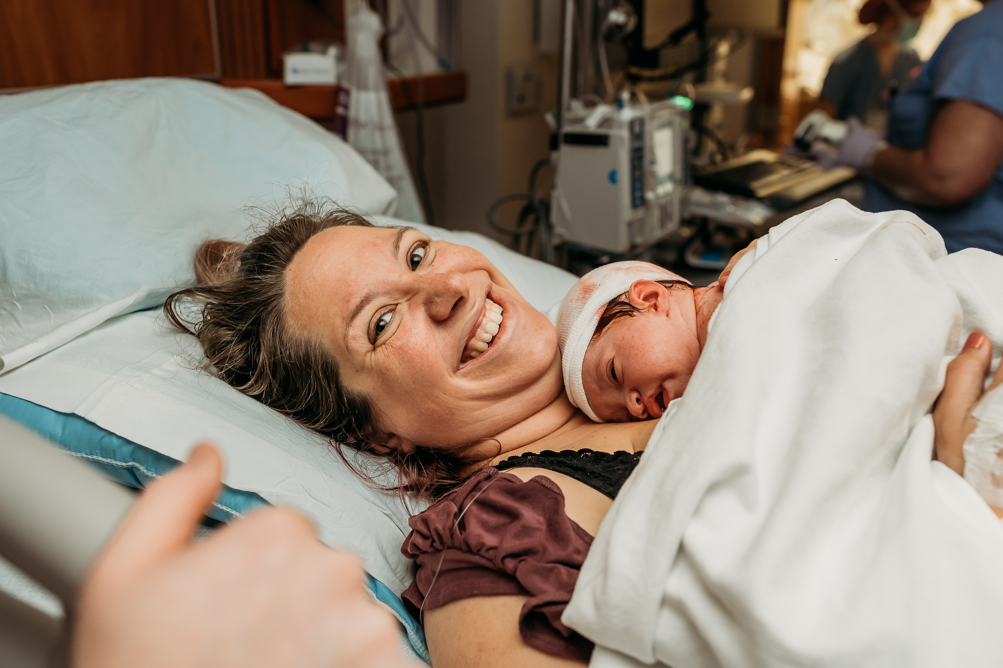 smiling mom laying in hospital bed after birth of baby