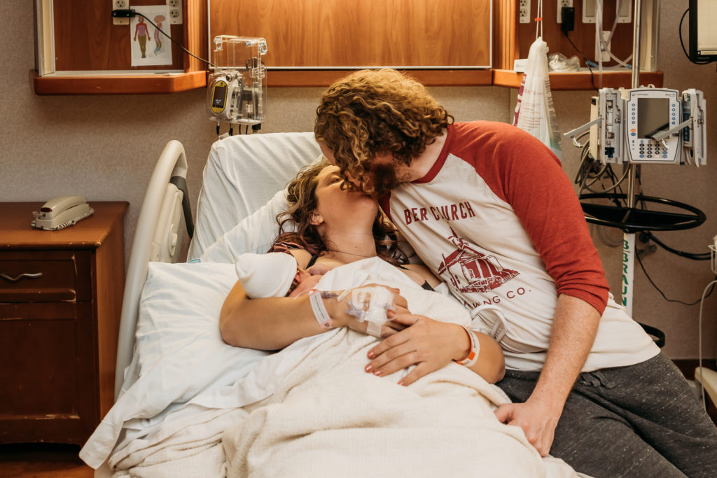 couple kissing in hospital bed after birth