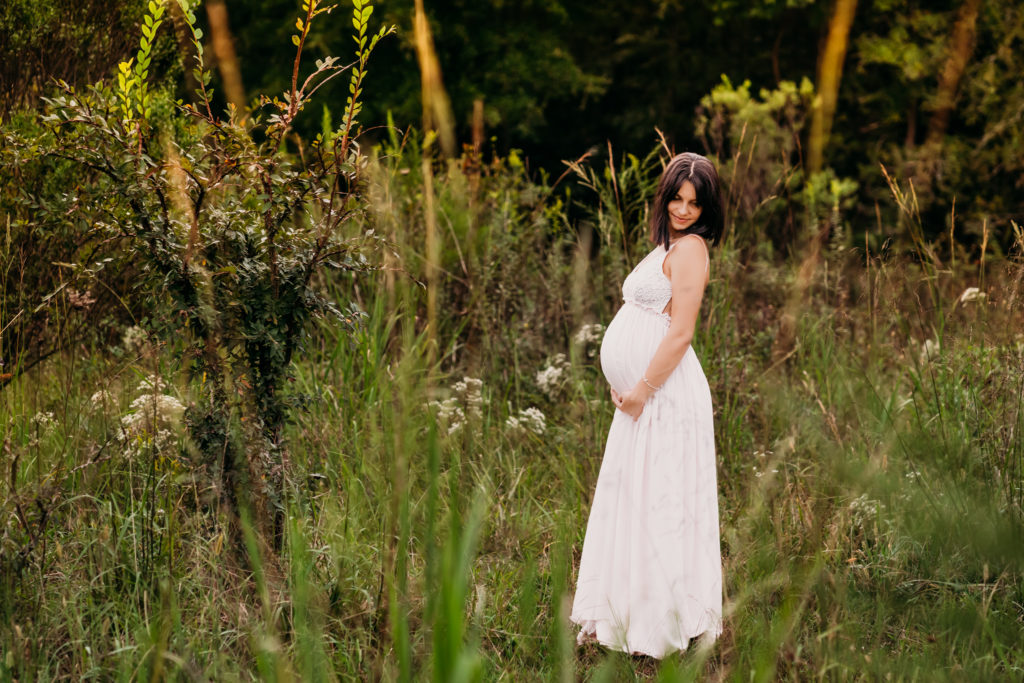 pregnant woman looking over her shoulder in green field