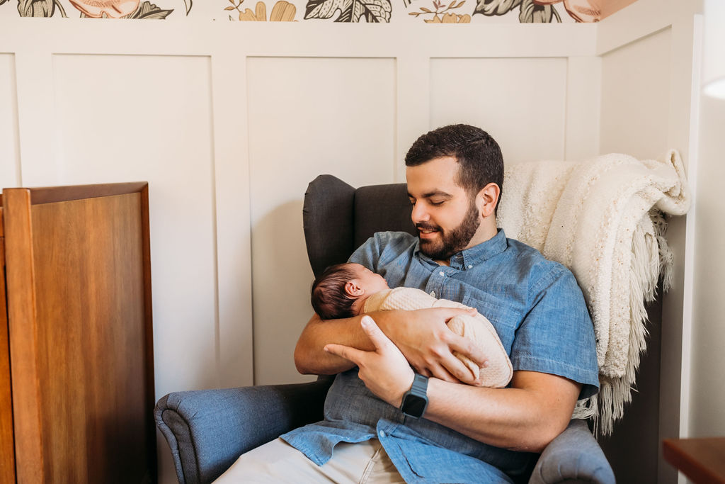 dad holding baby in nursery during lifestyle newborn session
