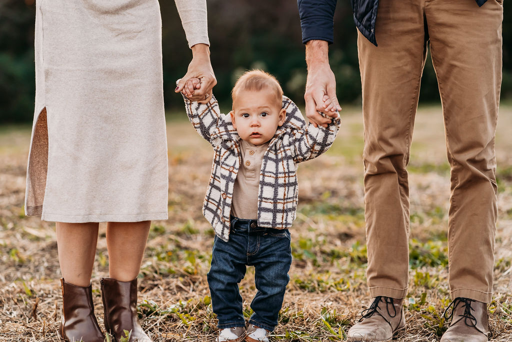 parents holding baby hands while standing