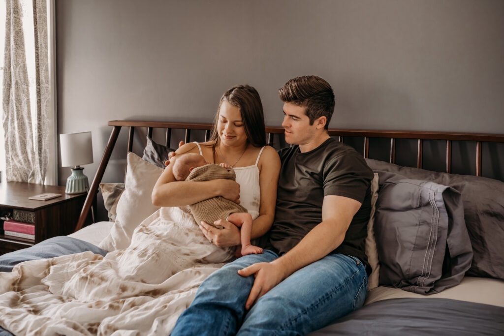 New parents holding and staring at baby in bed