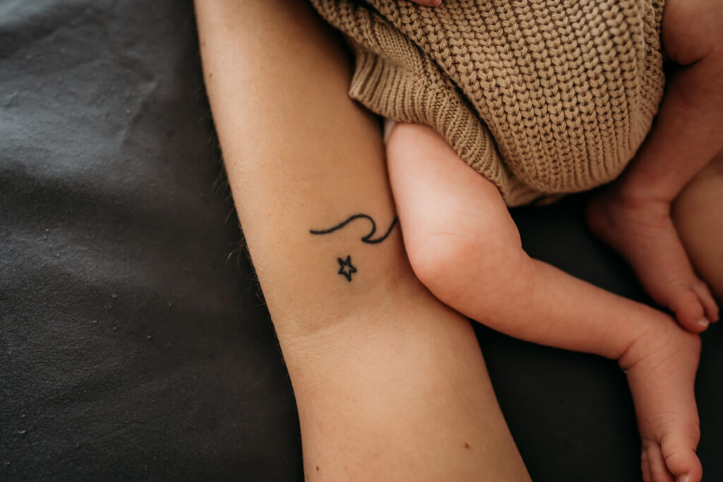close up of newborn baby legs and moms arm with tattoo
