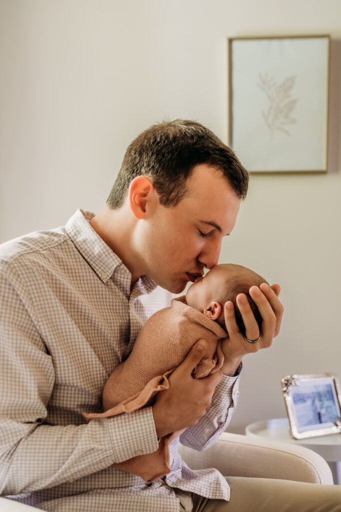 dad kissing newborn baby on the nose