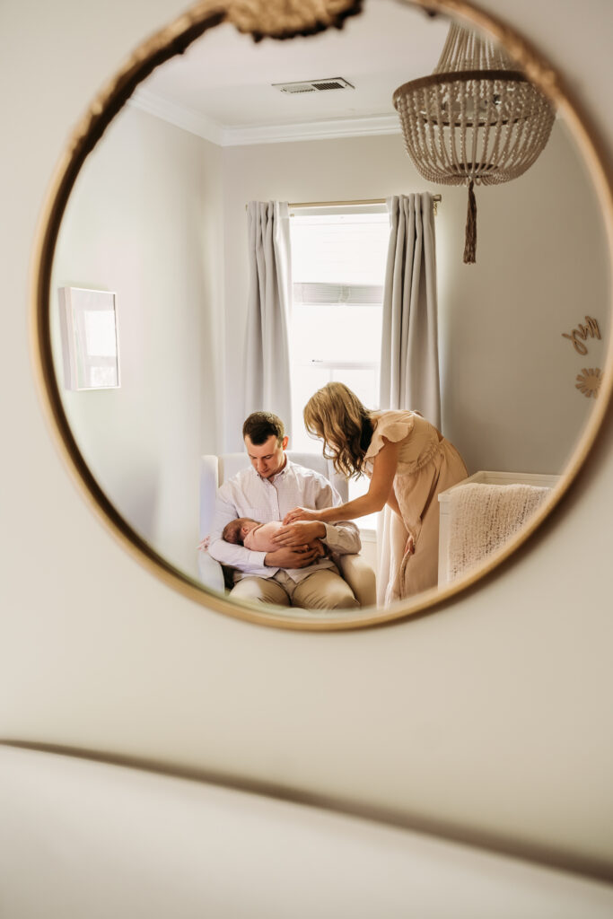 reflection in mirror of couple looking at newborn baby