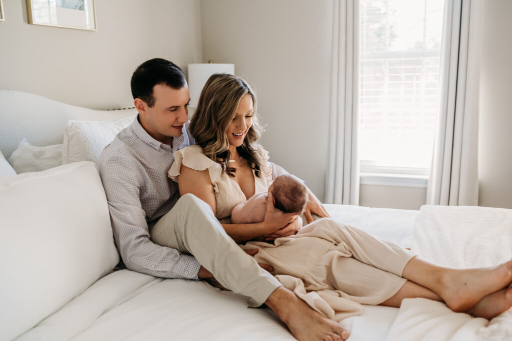 strong marriage couple holding newborn baby in bed