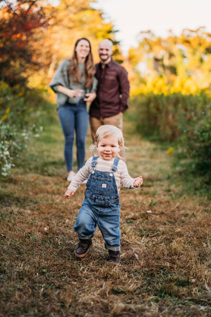 toddler running towards camera with parents in background