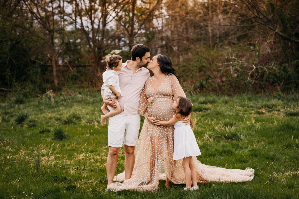 parents kissing while kids watch in favorite maternity dress