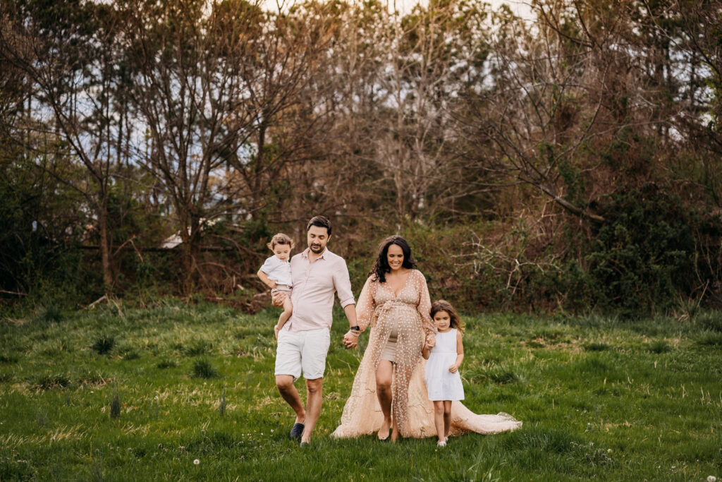 family walking in field in favorite maternity dress