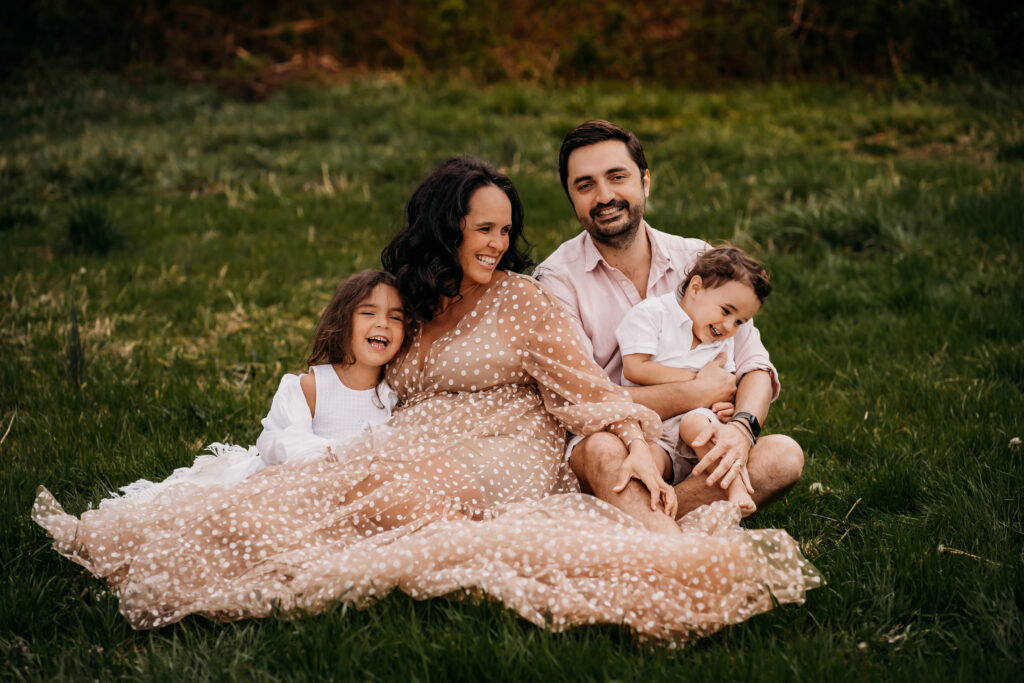 family together in a field in favorite maternity dress