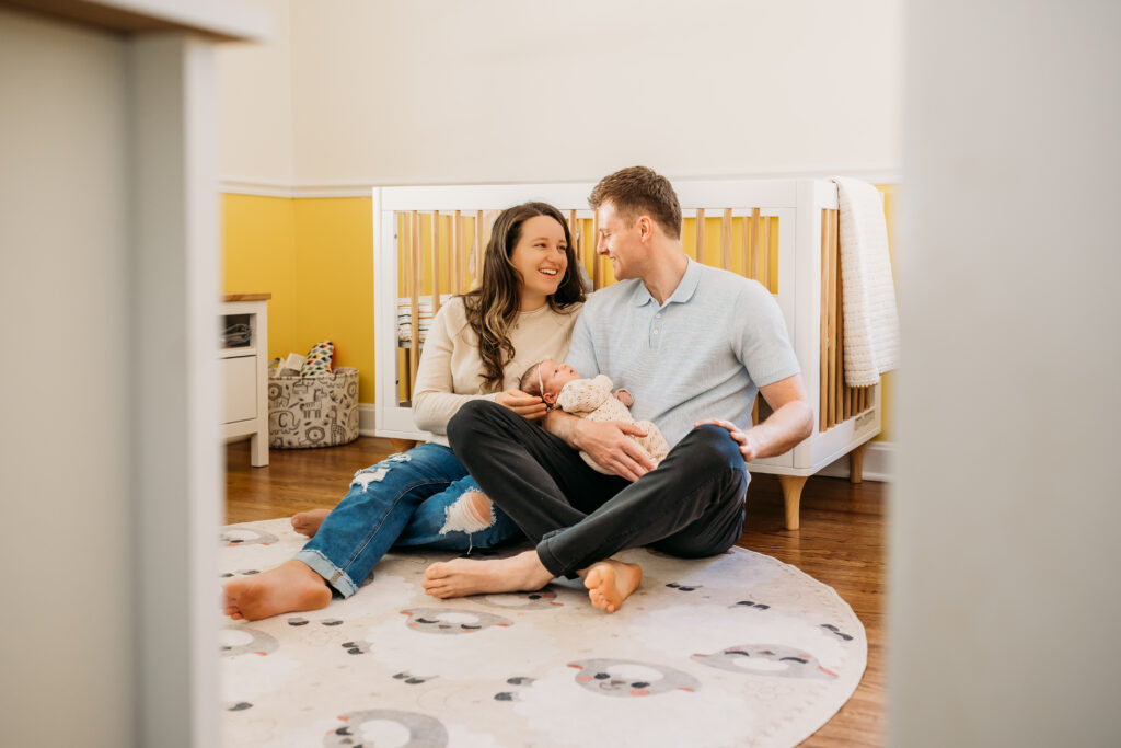 mom and dad in nursery holding baby near crib