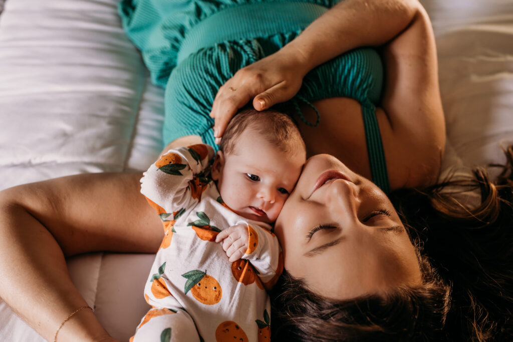 mom and baby face to face in bed during newborn photoshoot