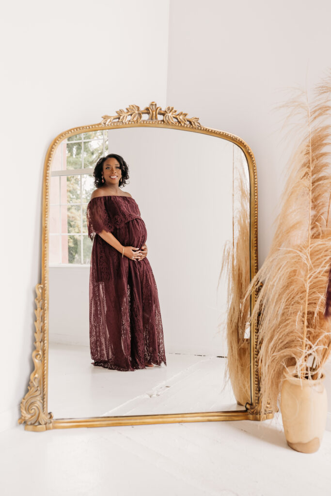 pregnant woman looking at her reflection in a vintage mirror for maternity pregnancy cravings photoshoot
