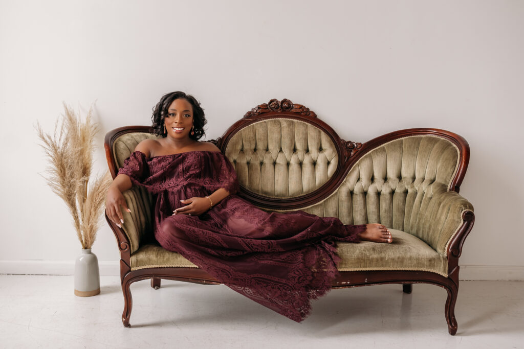 pregnant woman sitting on antique couch for maternity pregnancy cravings photoshoot