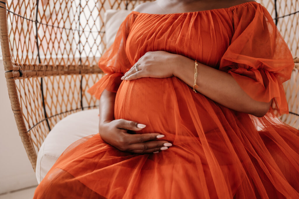 Close up of pregnant mom in orange tulle gown for maternity pregnancy cravings photoshoot